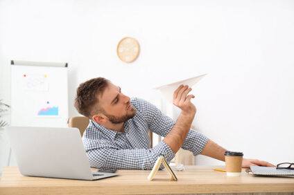 man preparing to fly paper airplane at office desk