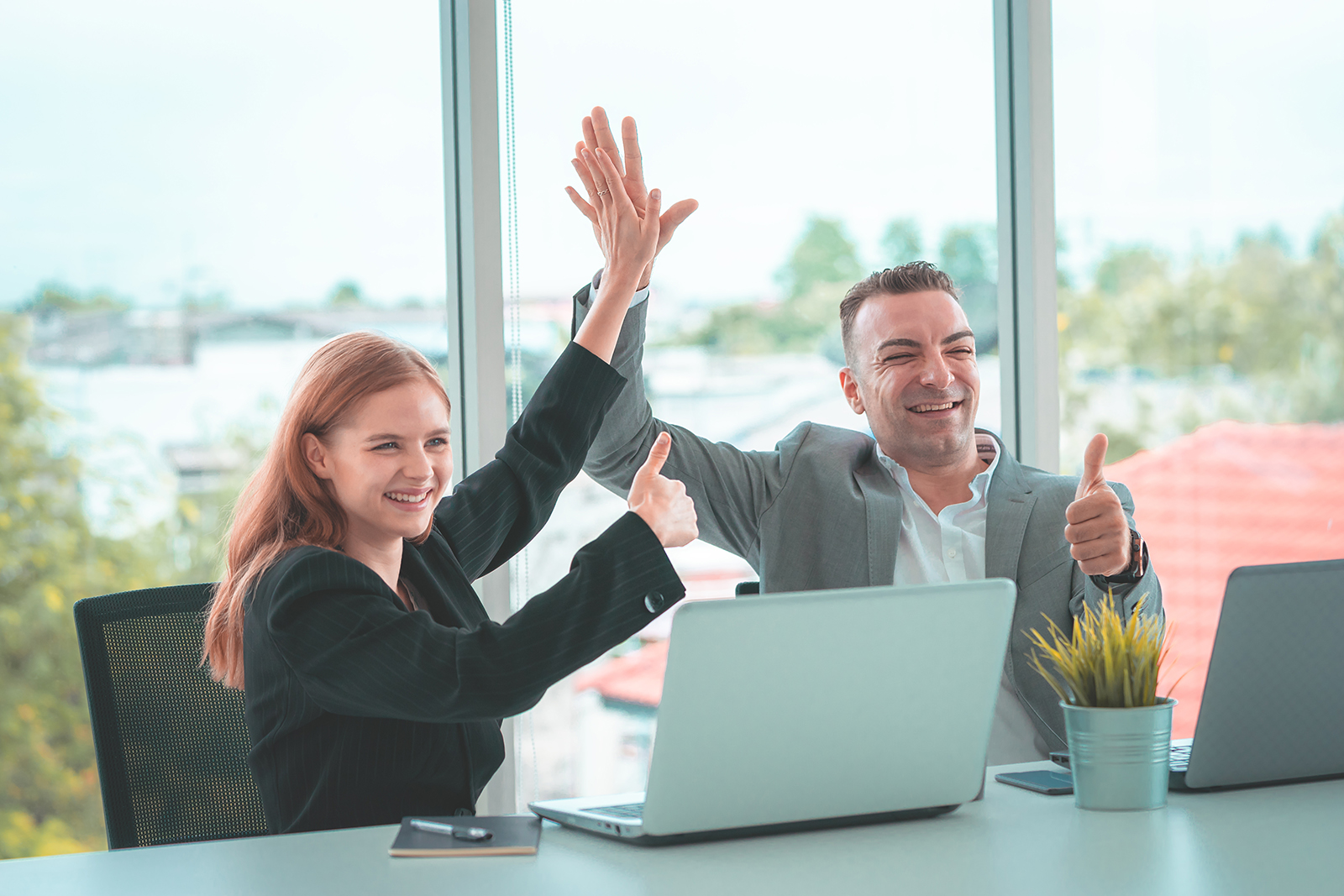 woman and man in office high-fiving and giving thumbs up