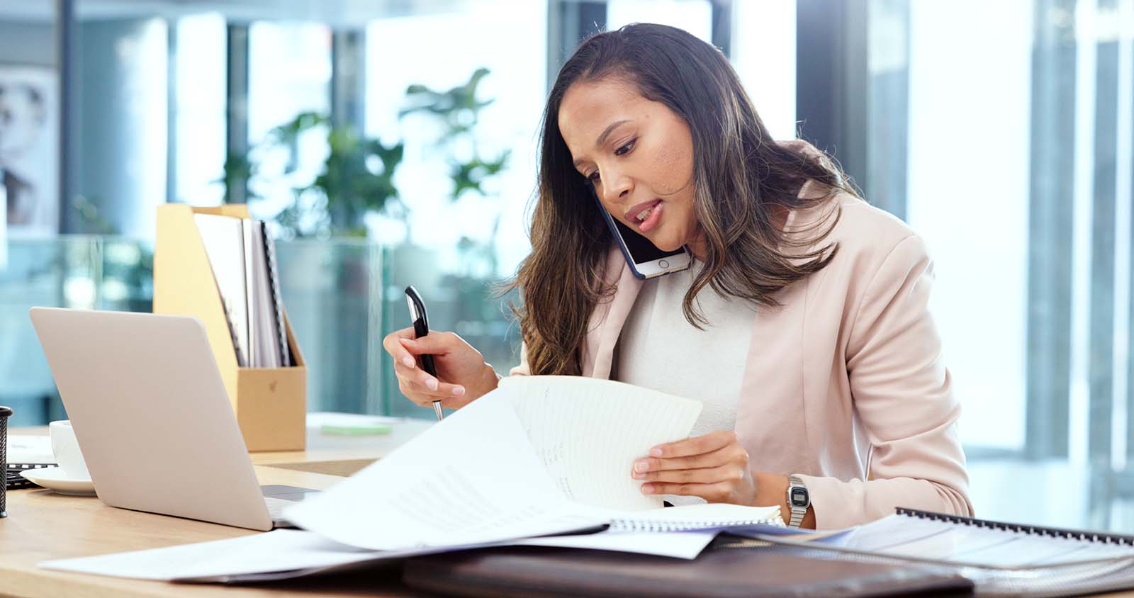 woman talking on phone while looking through papers
