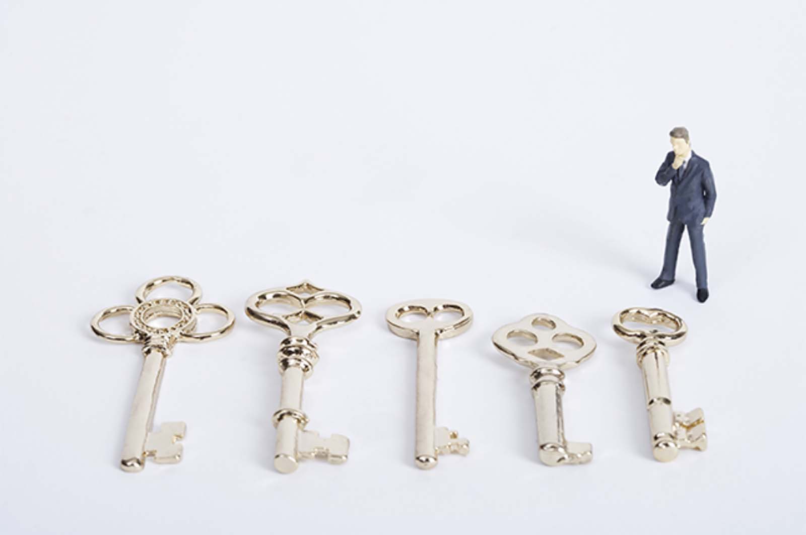 man standing, looking down at five giant golden keys