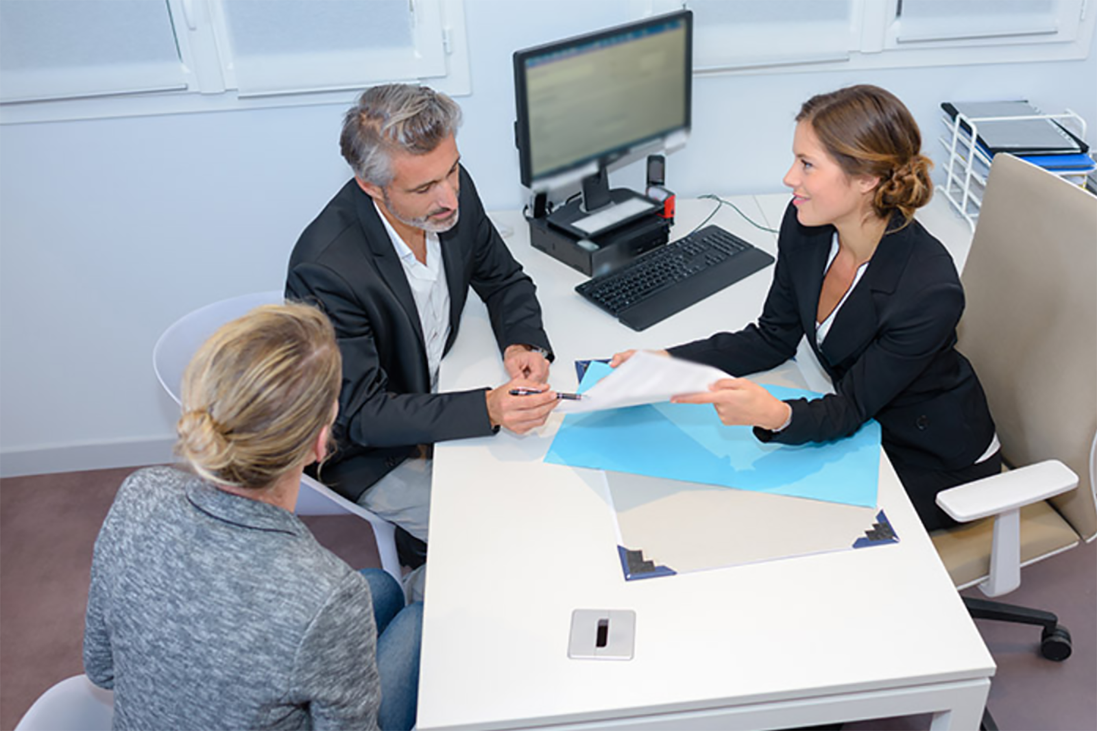 woman speaking across desk to couple