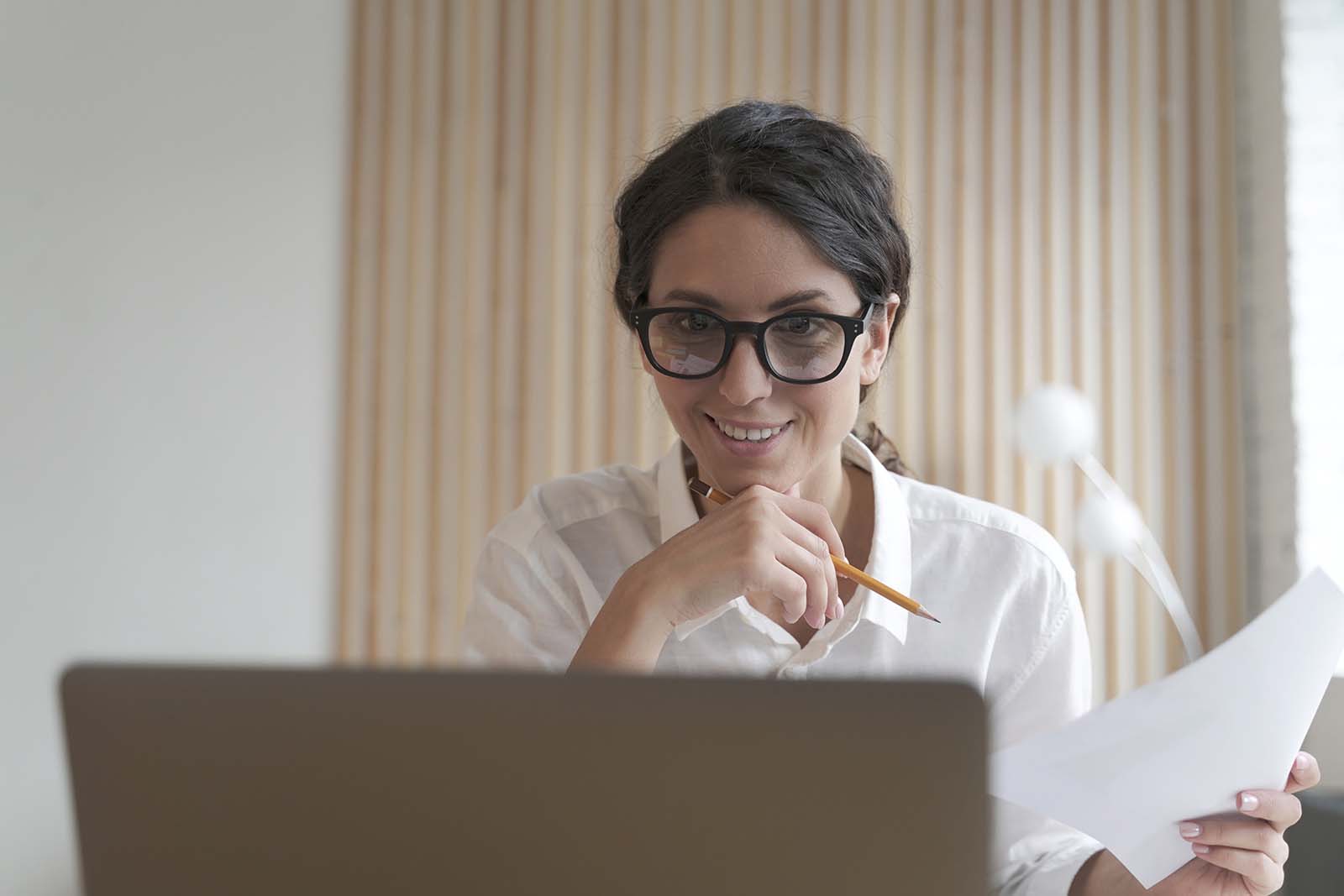 smiling woman wearing glasses, looking at computer screen