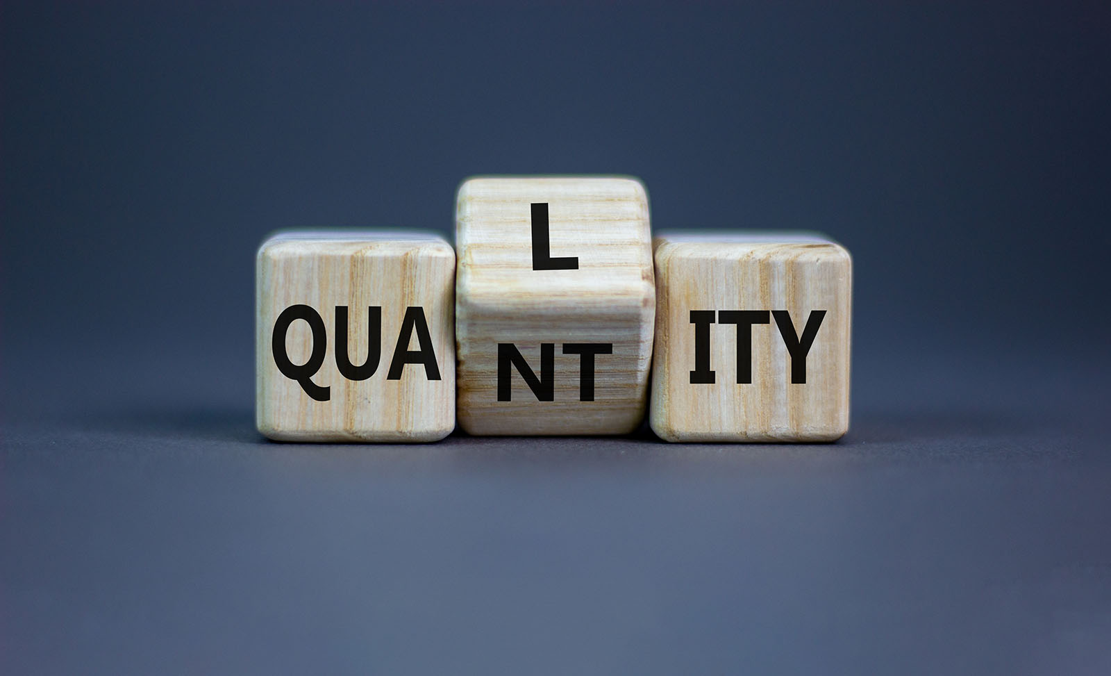 letter blocks with middle section rotating to change word from "quantity" to "quality"