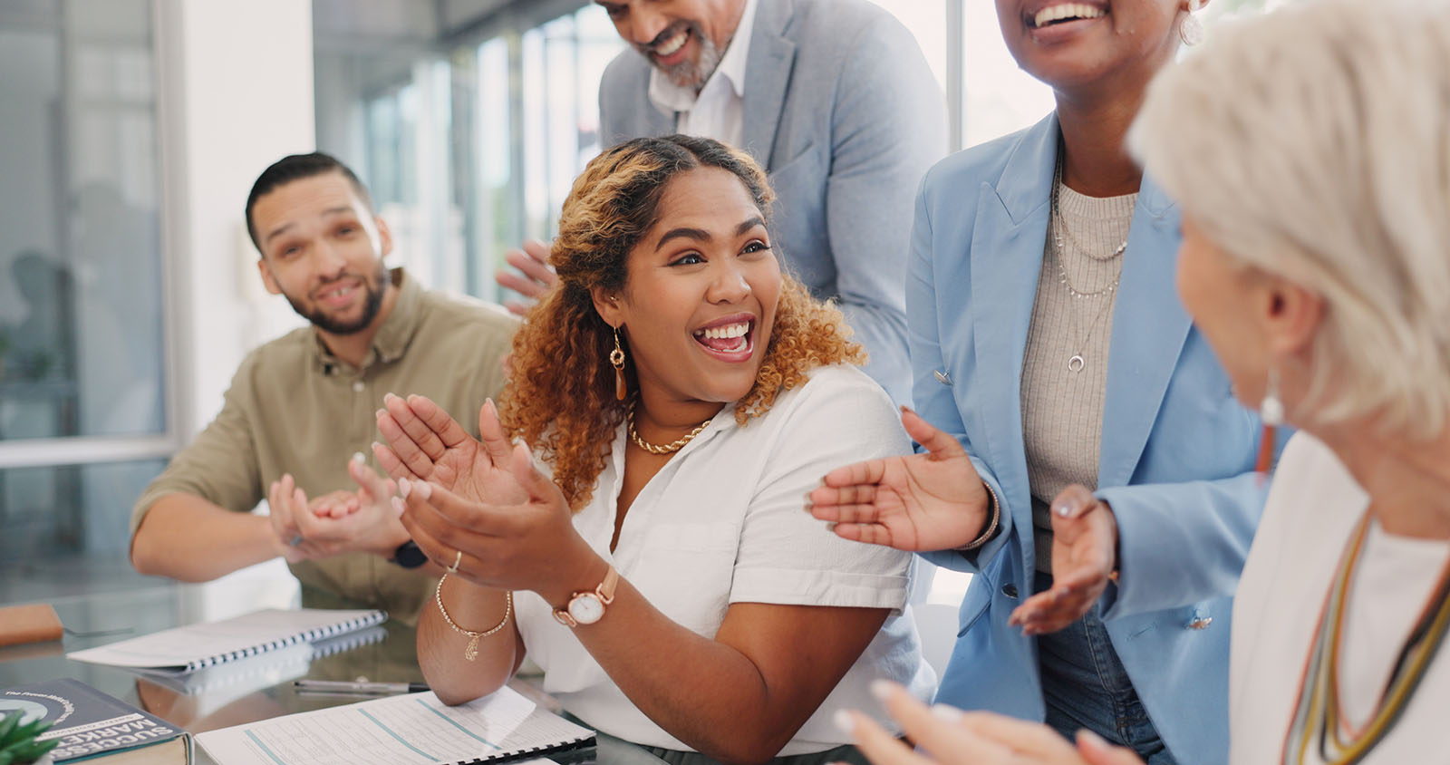 five people applauding in business setting, recognizing coworker