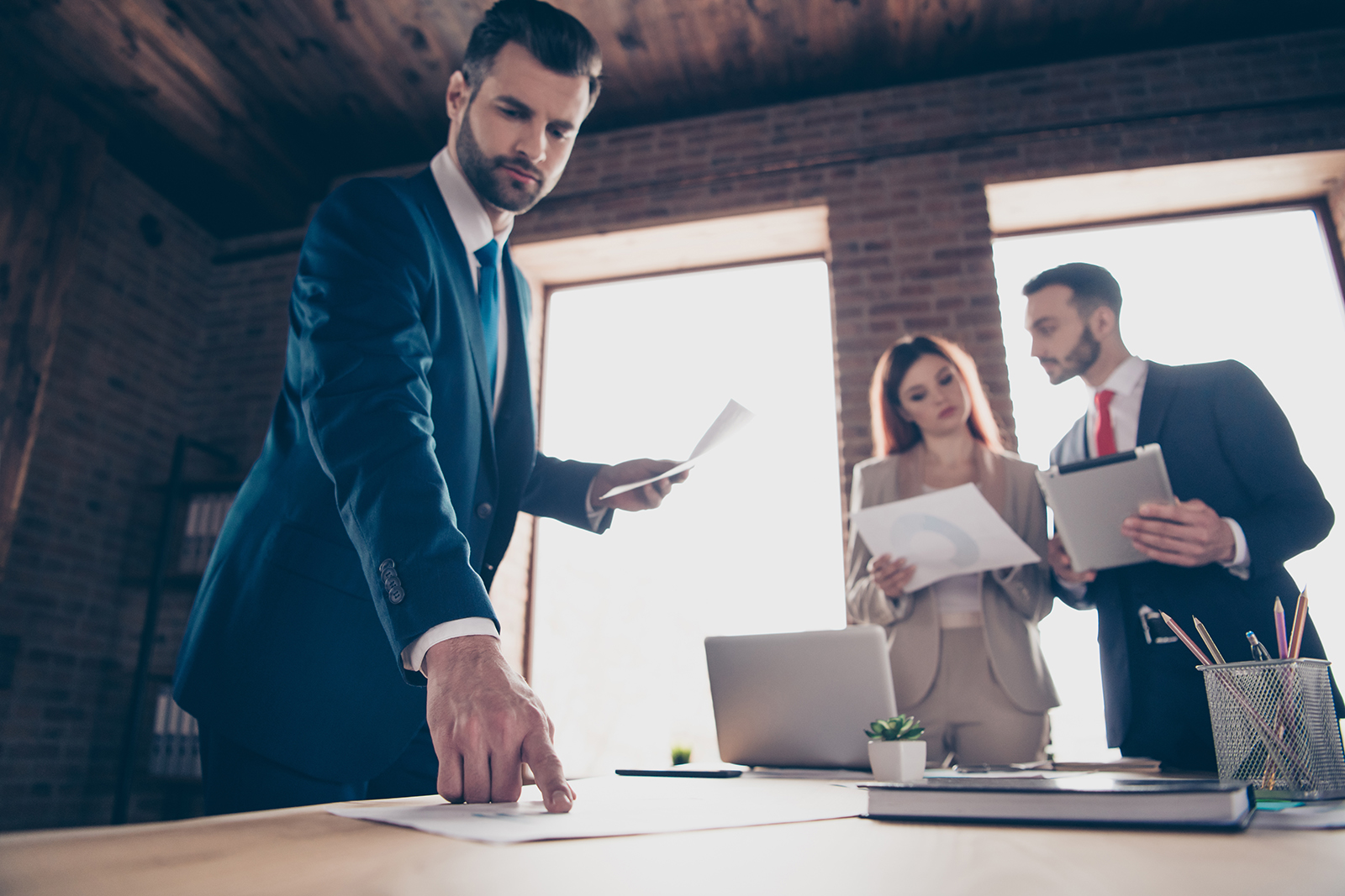 three people standing and talking around table in brick conference room