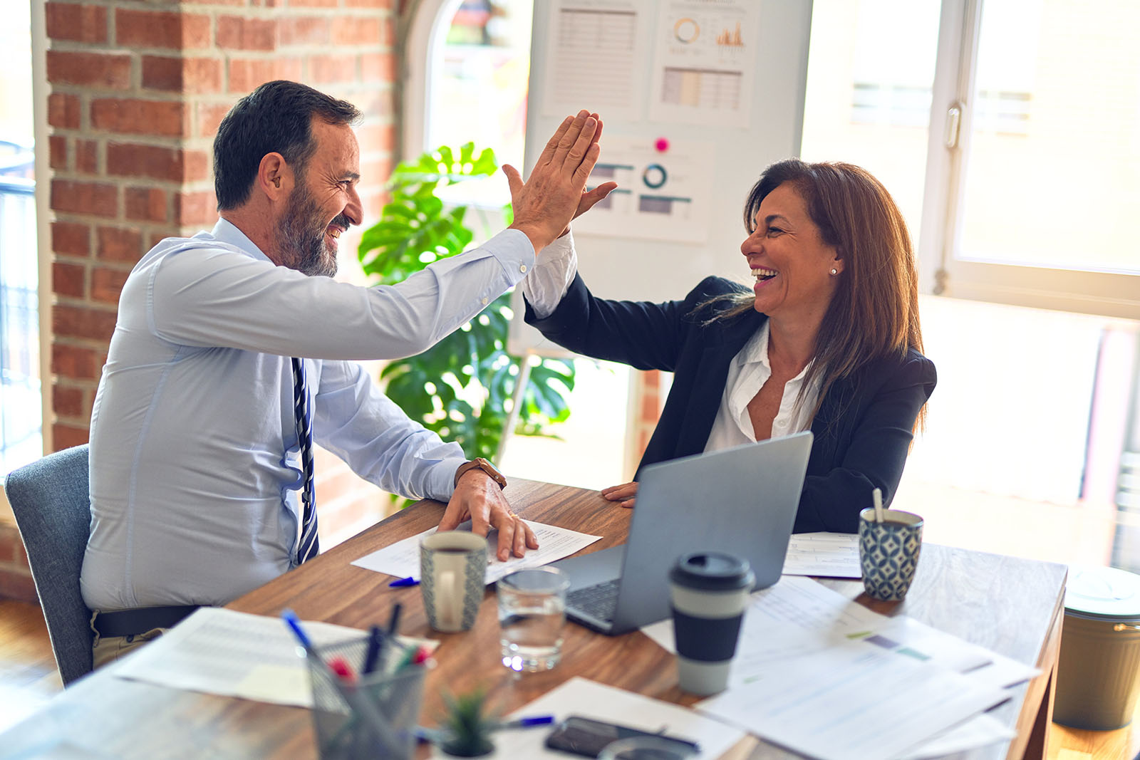 man and woman high-fiving each other in office