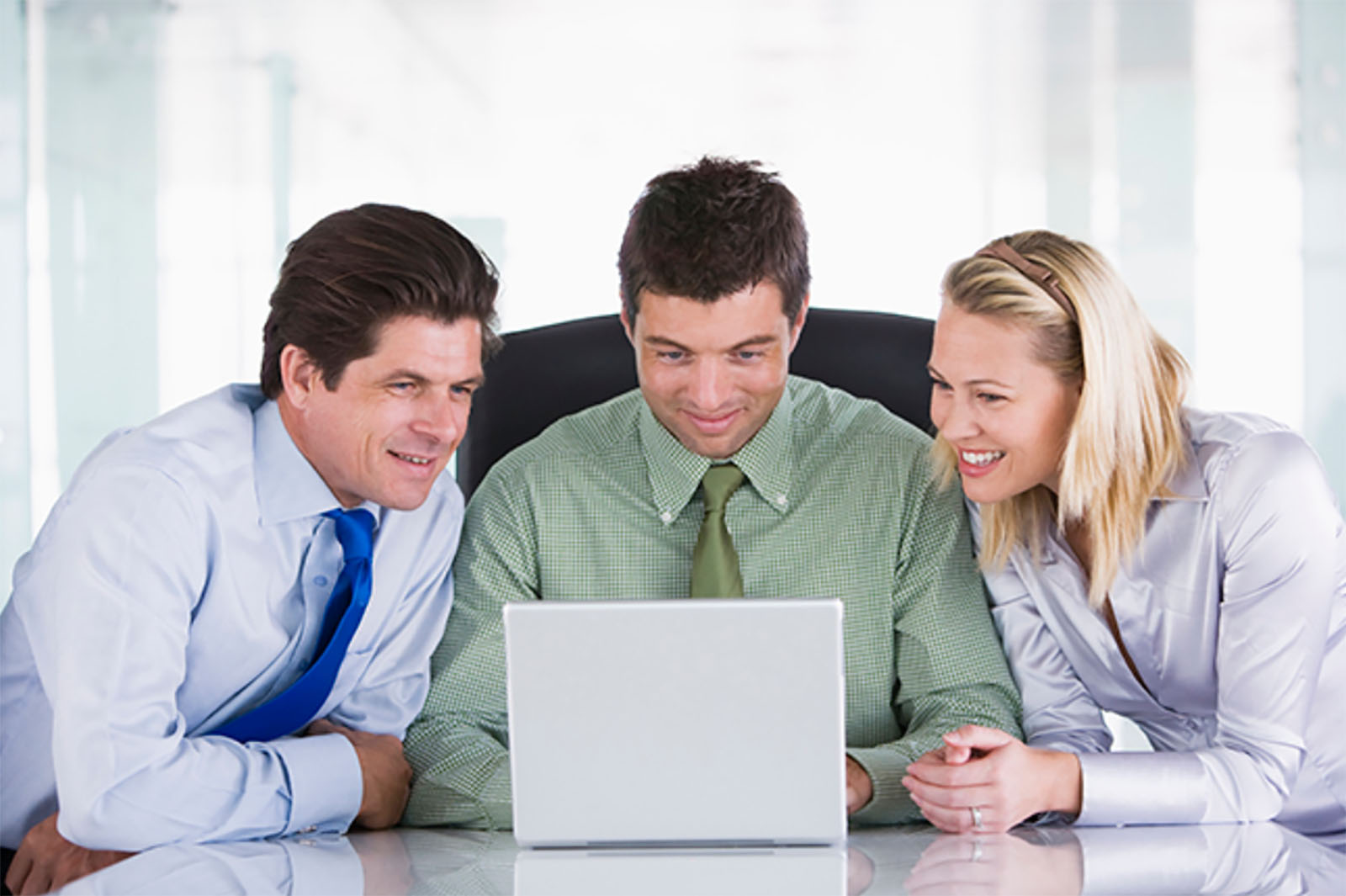 three businesspeople looking at laptop and smiling