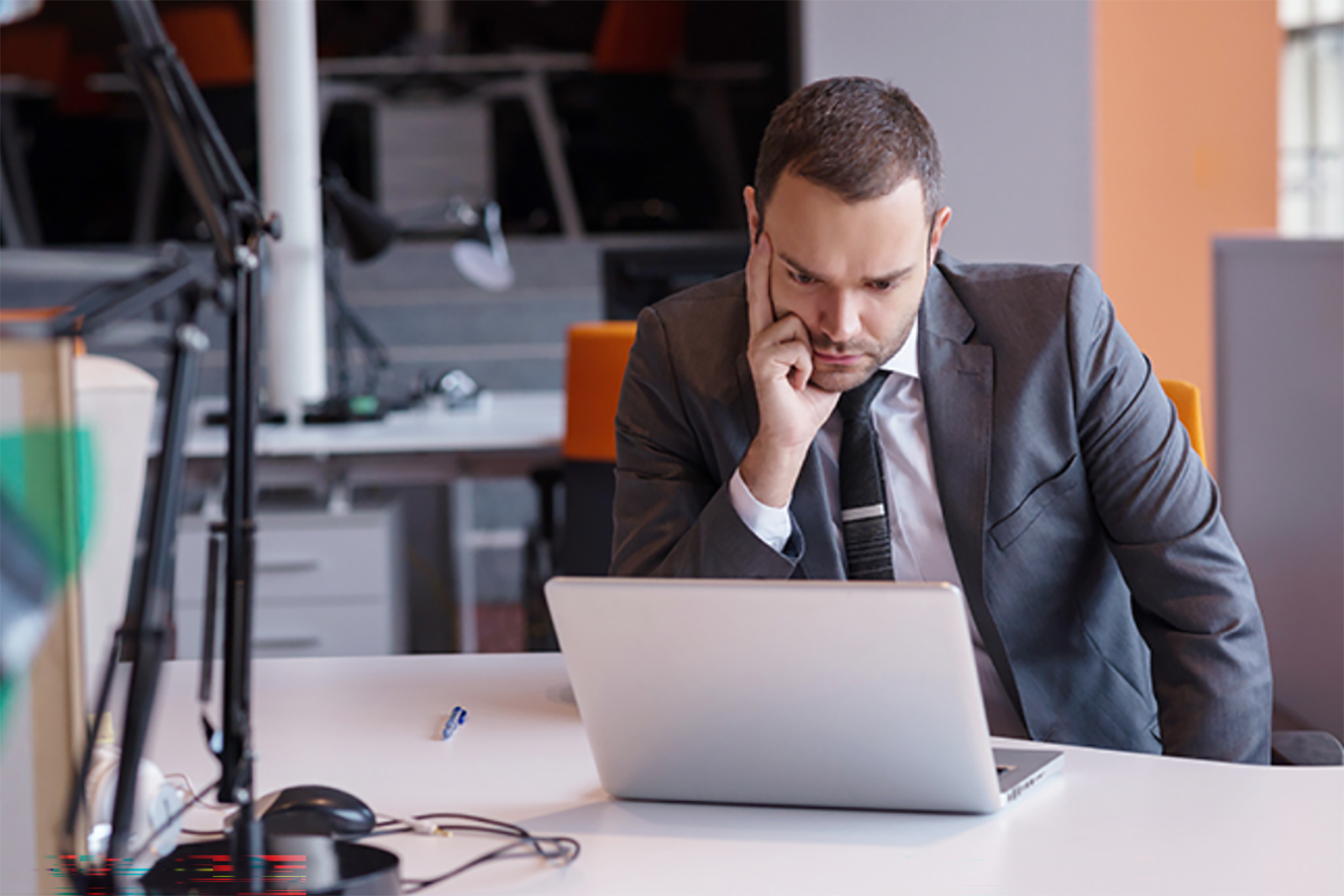 young man in suit staring at laptop screen