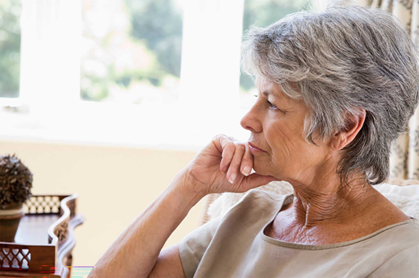 Older businesswoman pondering, seated by window