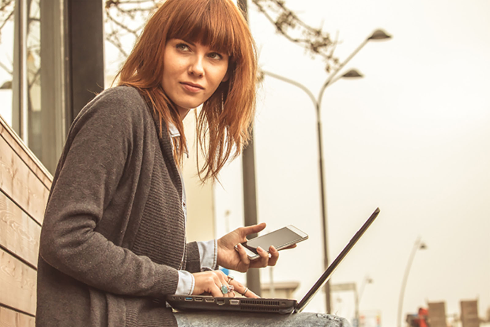 woman sitting outside with laptop and smartphone