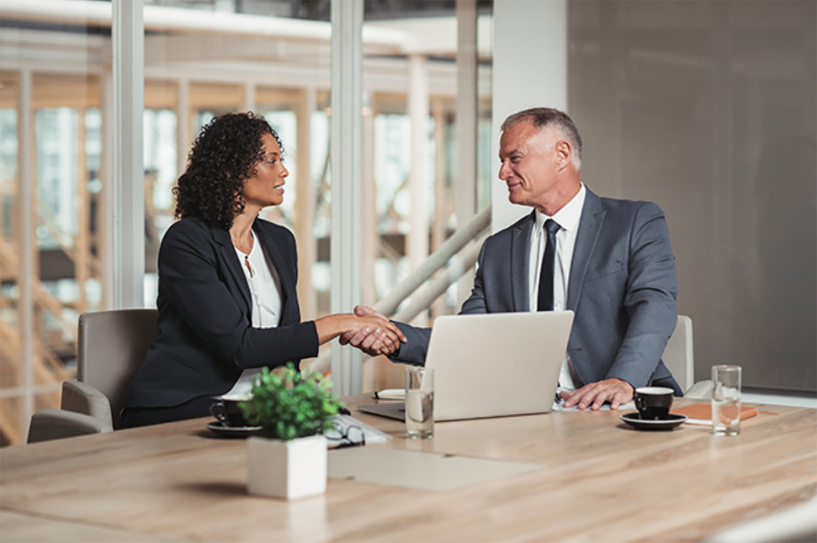 Woman and man shaking hands in office conference room