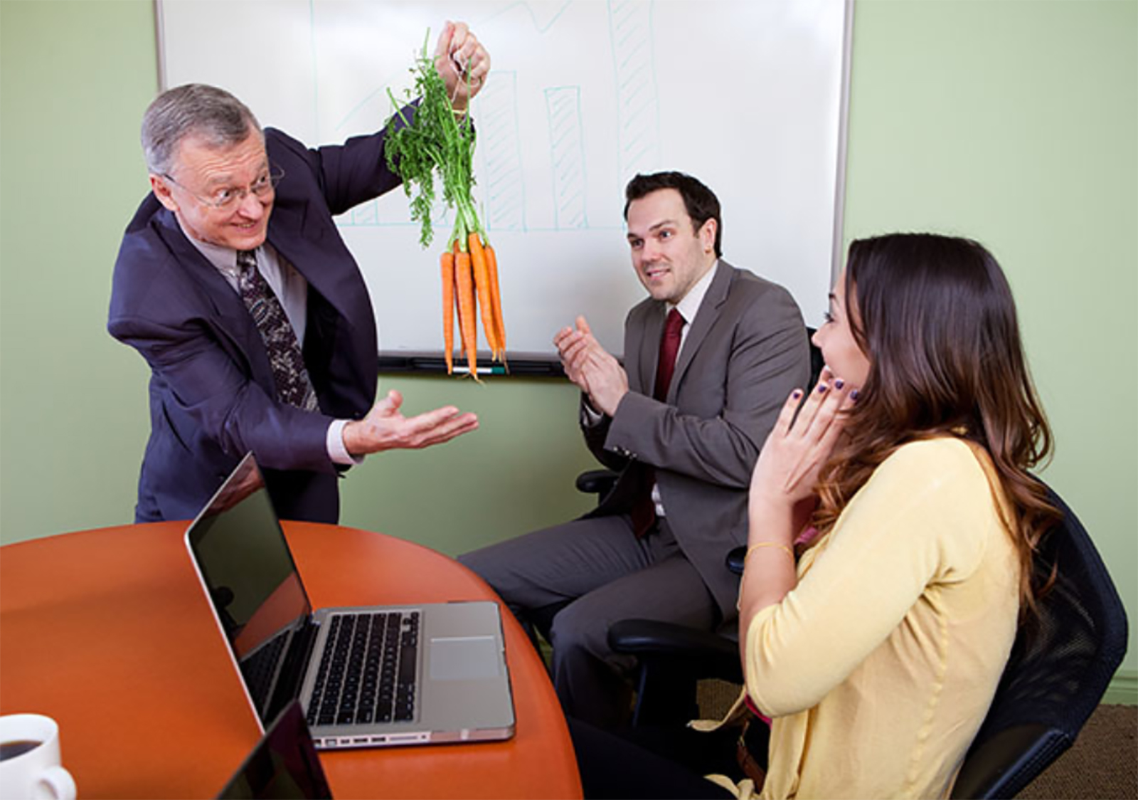 manager holding up carrots in front of employees